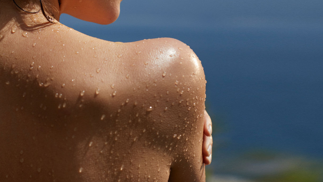 Vrouw in achteraanzicht met waterdruppels op haar huid.